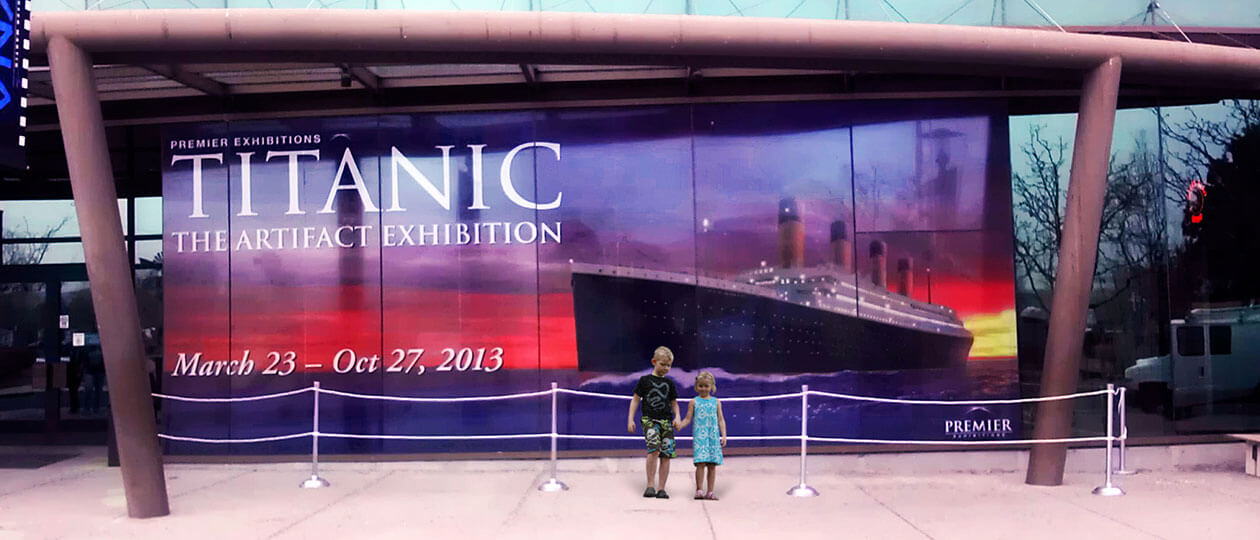 Children stand in front of Titanic exhibition banner wall